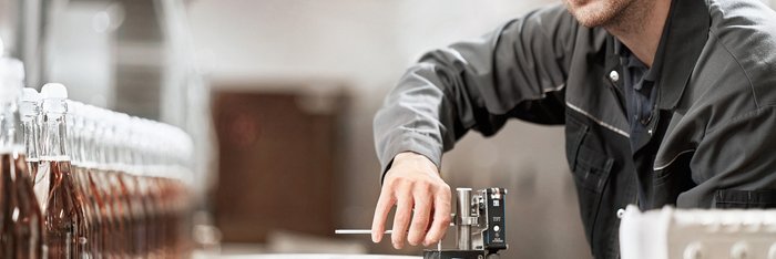 Das Foto zeigt einen Mann der an einer Maschine steht und daran arbeitet