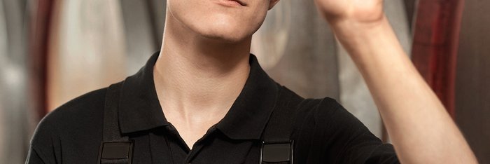 Das Foto zeigt einen jungen Mann der ein Glas mit einem Flüssigkeit vors Licht hält